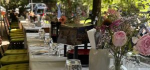 GEdeckter Biergartentische mit Gläsern, Tellern, Servietten und Blumenbouquets