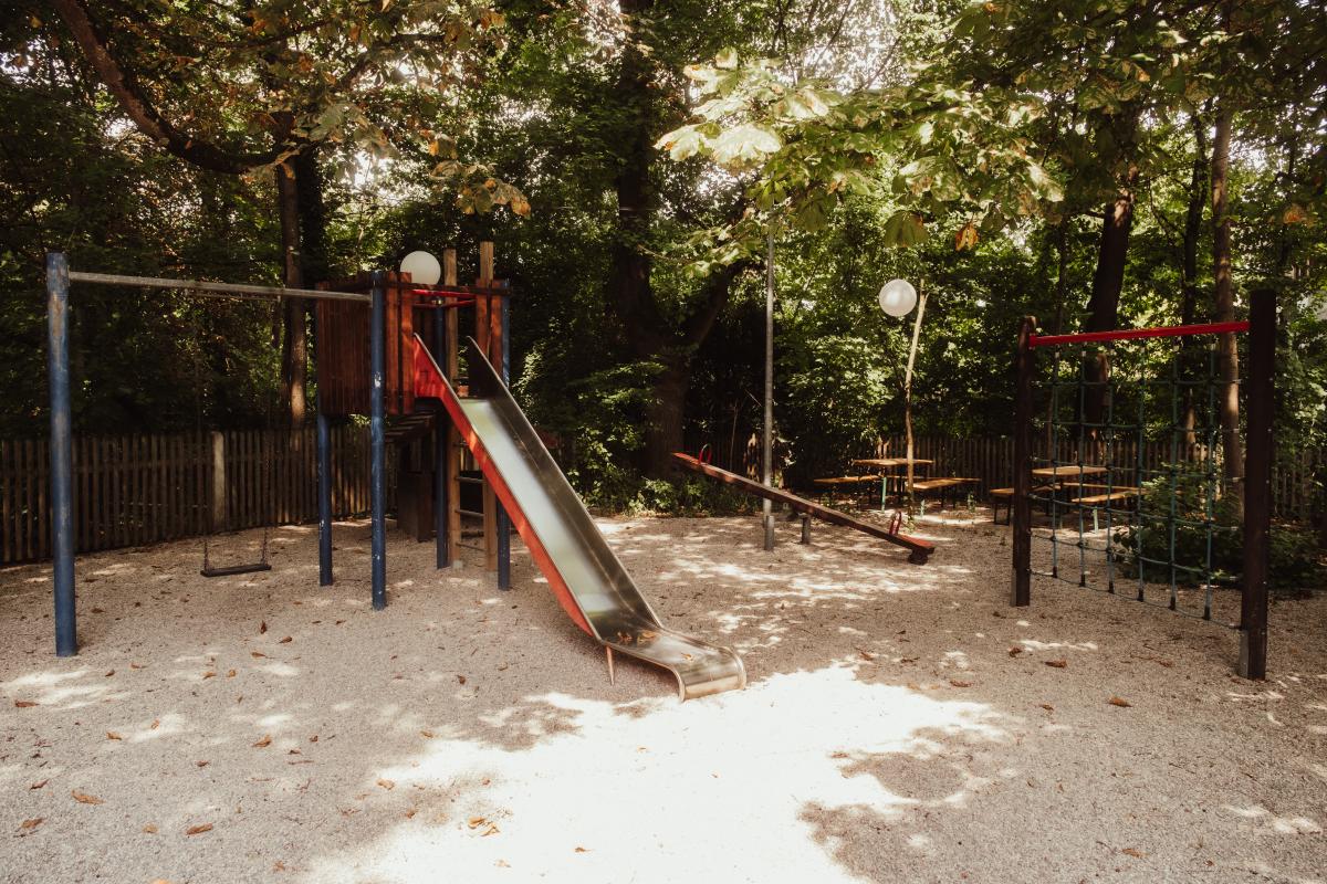Rutsche und Kletterturm auf dem schattigen Spielplatz der Emmeramsmühle