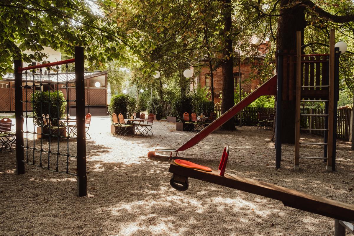 Biergarten der Emmeramsmühle mit schattigen Sitzplätzen und historischem Backsteinhaus